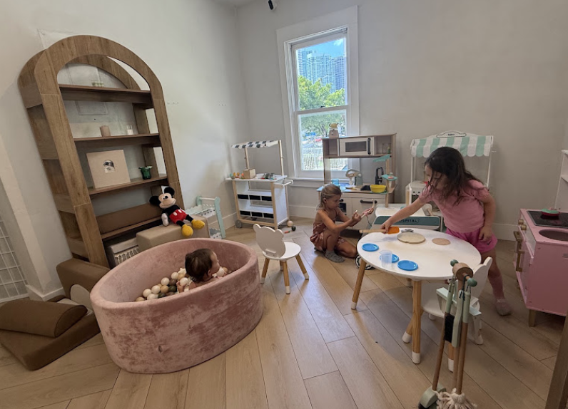 Pretend-play room with kitchen sets, a table, and a small ball pit