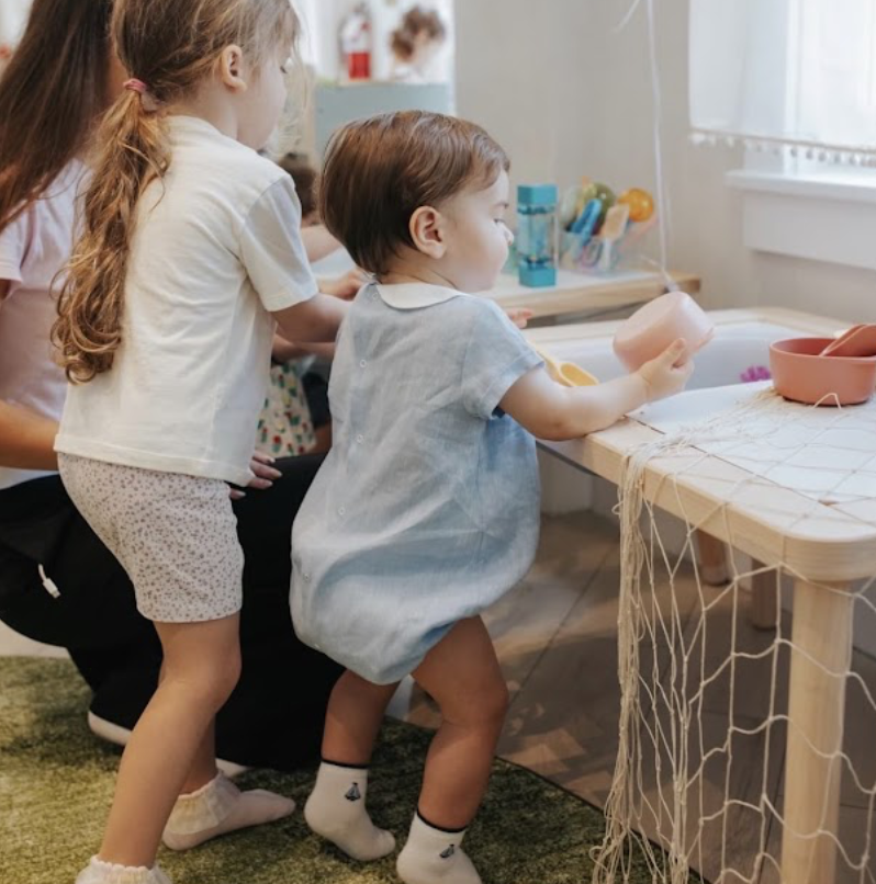 Toddler at a play table with bowls and toys