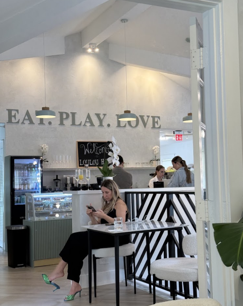 Guests relaxing at the cafe beside the 'Eat. Play. Love.' wall