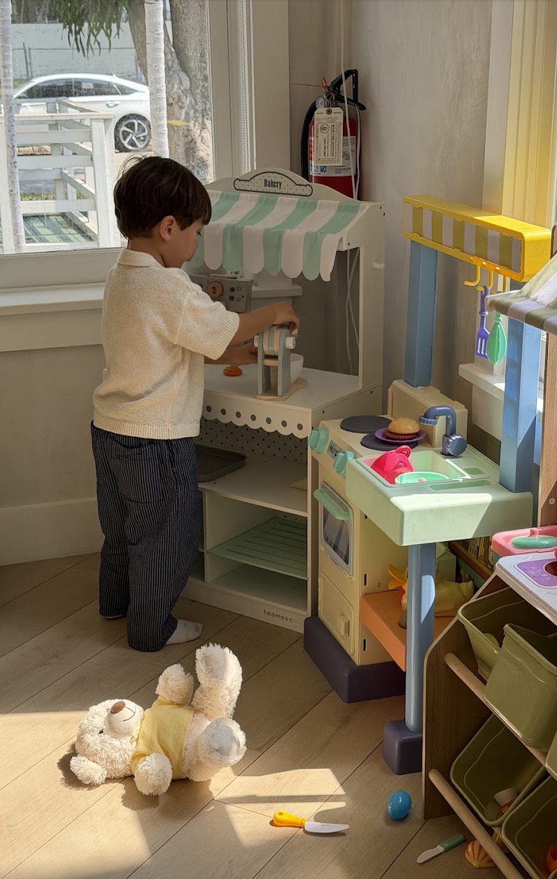 Child at a pretend bakery and toy kitchen in the Play Area
