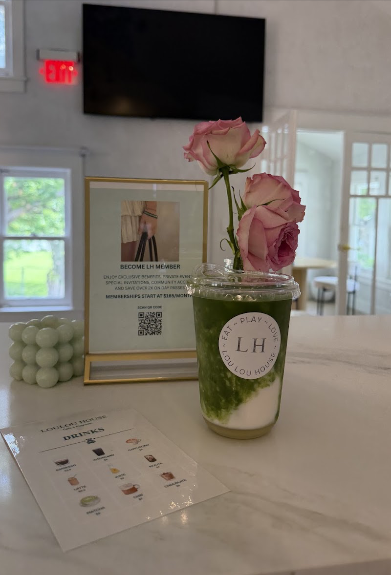 Iced matcha next to a bouquet of pink roses at the cafe