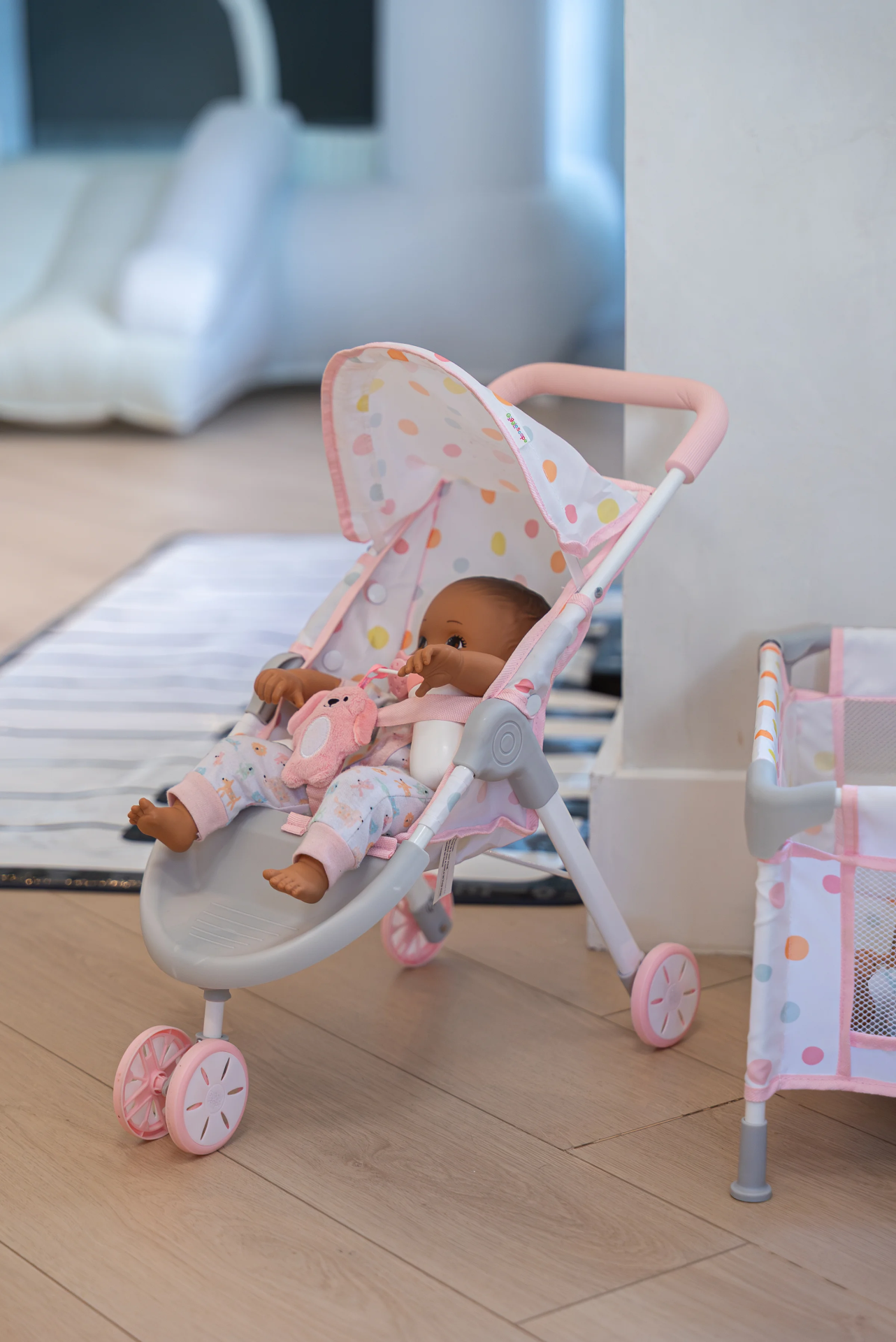 A doll resting in a toy stroller on the Play Room floor.