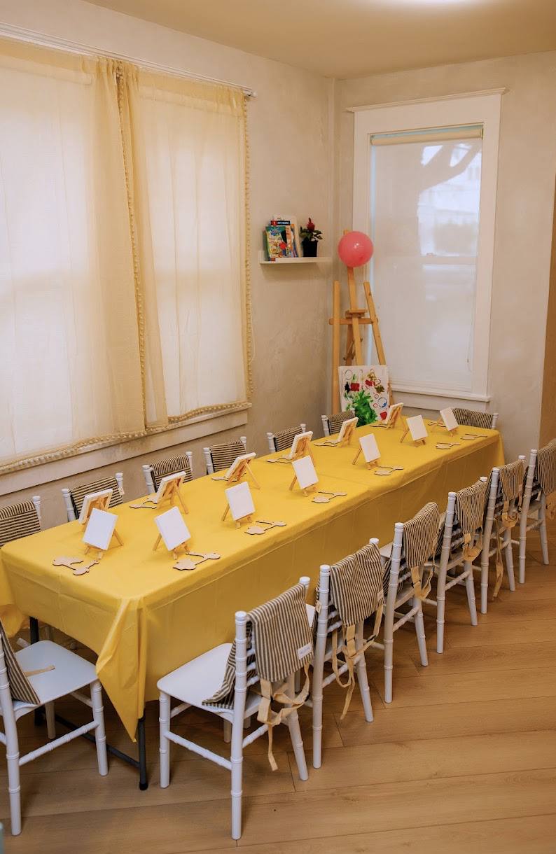 Birthday art activity setup with small easels and canvases on a yellow table