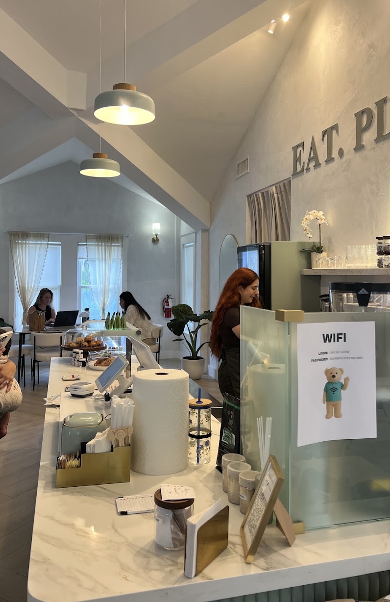 Cafe counter with pastries and guests working in the background