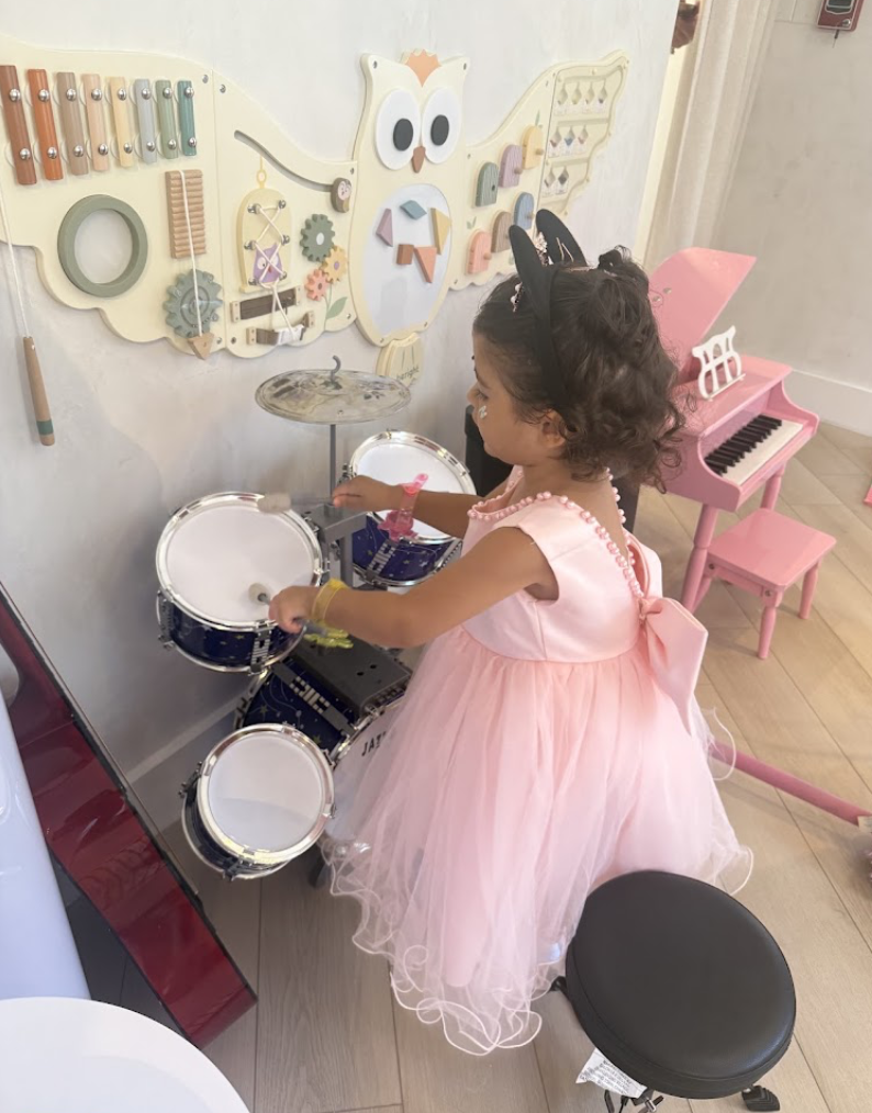 Child at the music corner with a toy drum set and pink piano