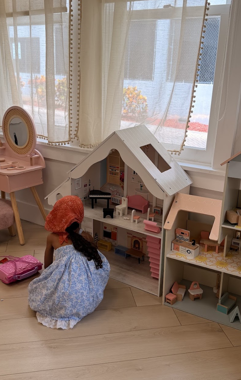 Child playing with a large dollhouse beside the vanity corner