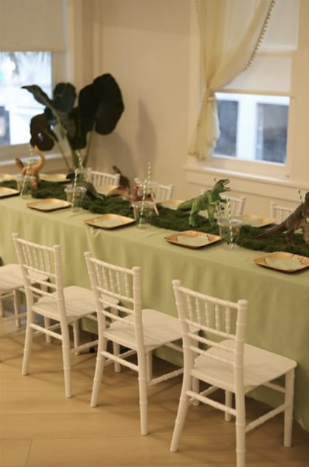 LOULOU HOUSE common space set with a sage table runner and playful dinosaur centerpieces